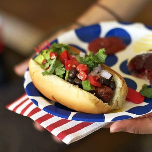 Hot dog on a plate with toppings.