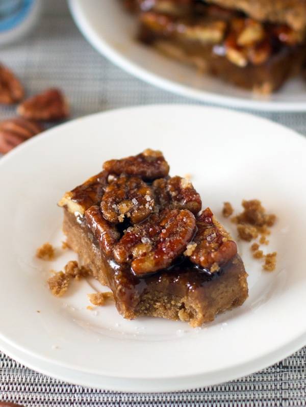 Salted maple pecan pie bar on a plate with a bite taken out.