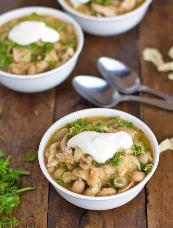 White chicken chili in three bowls with sour cream.