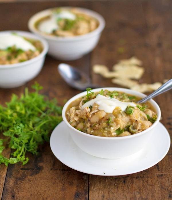 White chicken chili in three bowls with sour cream.