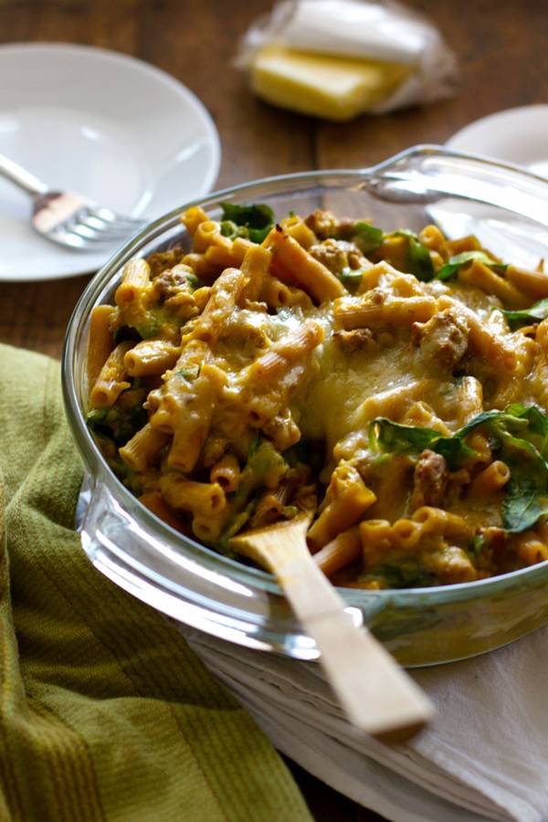 Baked rigatoni in a clear glass bowl with a wooden spoon.