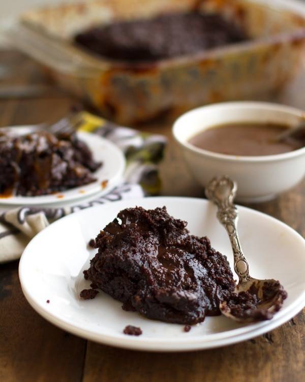 Chocolate caramel cake on a white plate with a spoon.