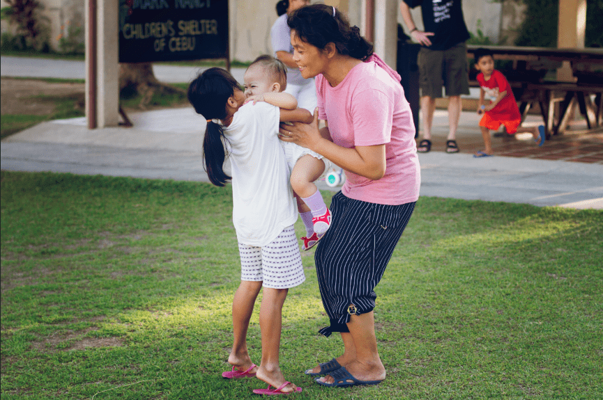Woman playing with young girls outside.