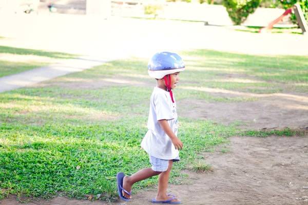 Young boy playing outside wearing a helmet.