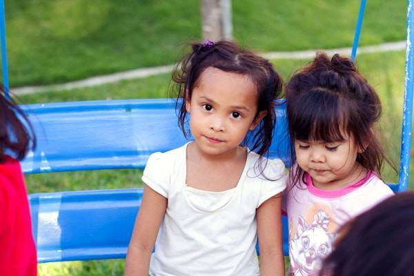 Young girls sitting on a swing.
