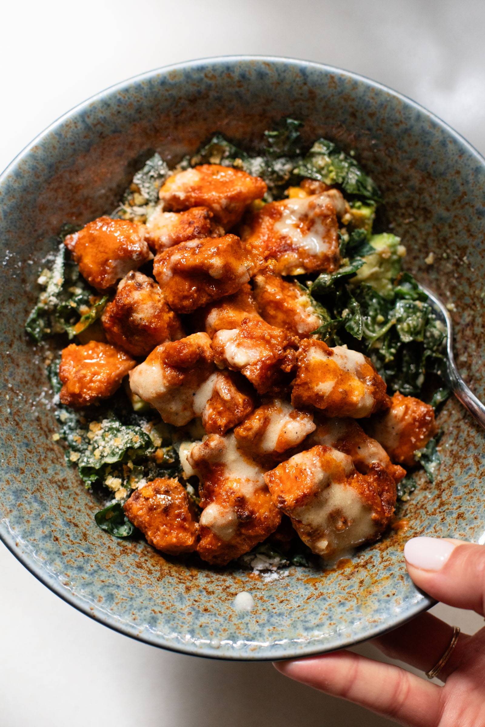 Buffalo tofu on kale caesar salad with avocado