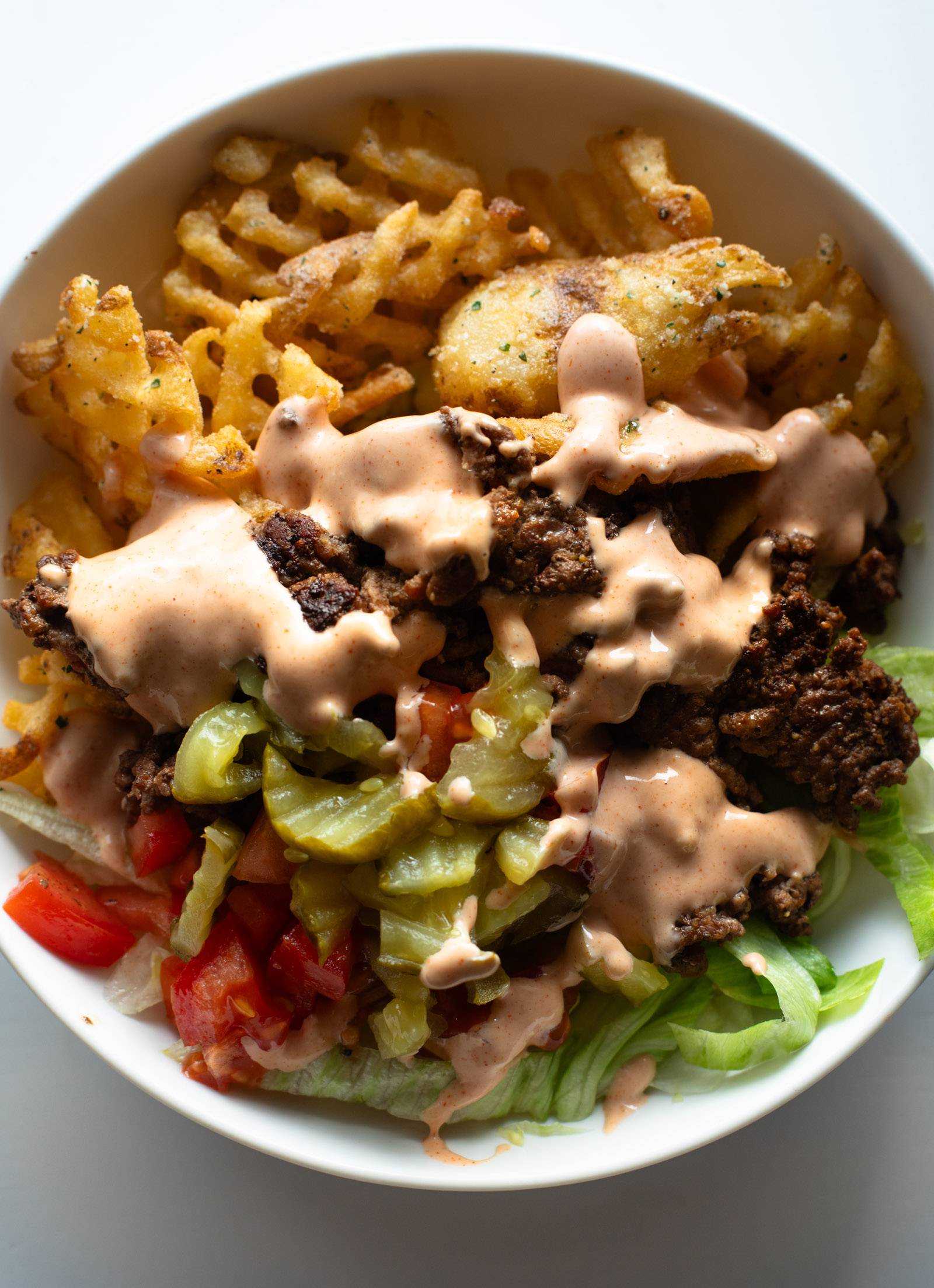 Burger bowl with lettuce, pickled, tomatoes, and house sauce.