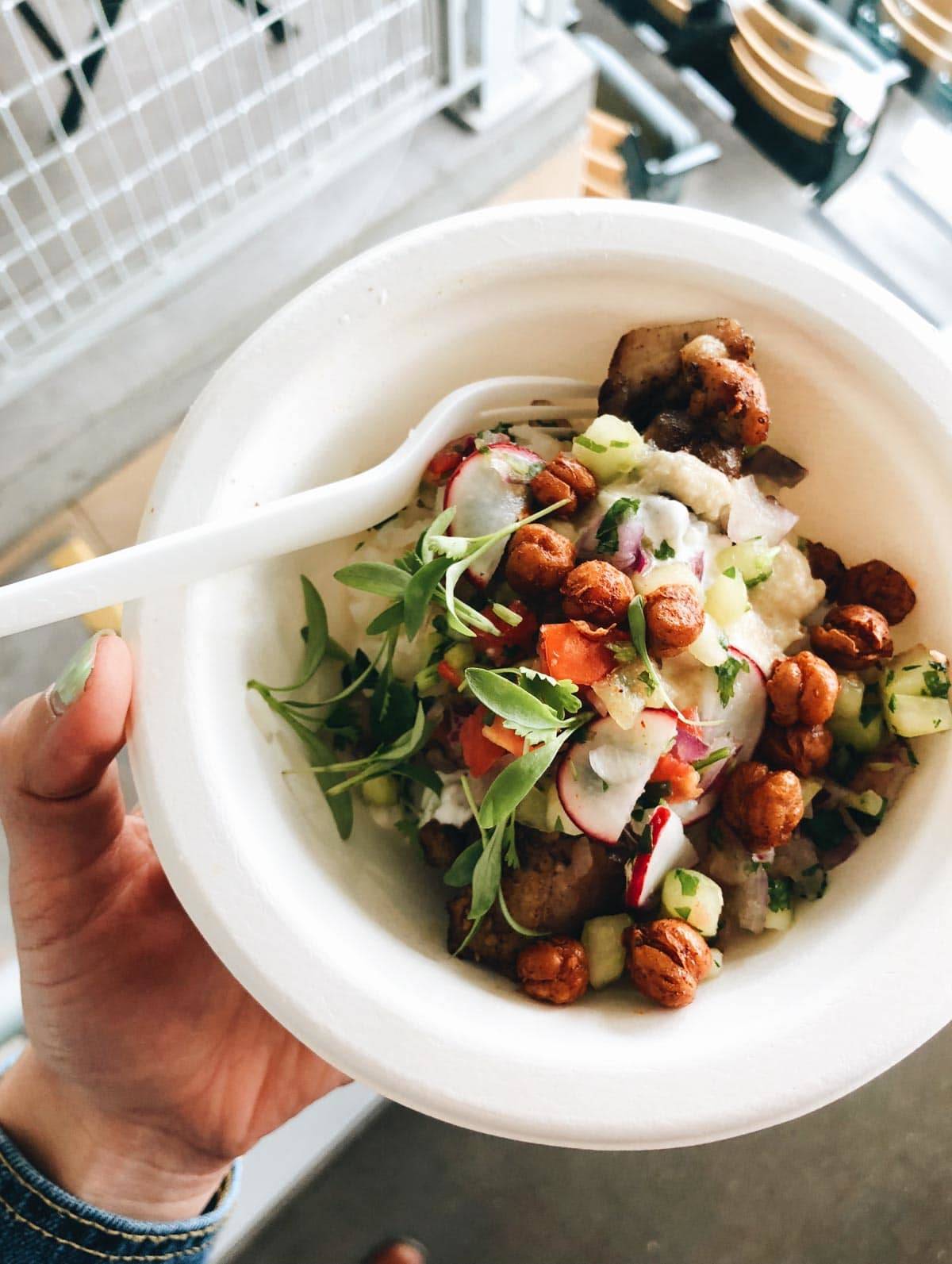 Chicken with roasted chickpeas and vegetables in a bowl with a fork.