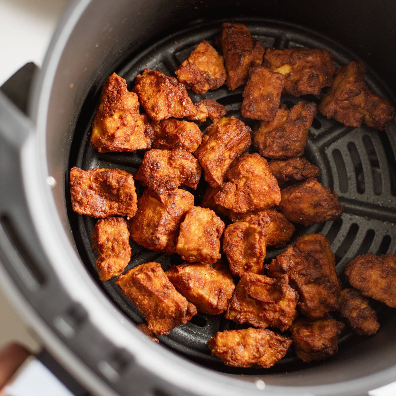 Crispy tofu in an air fryer basket.