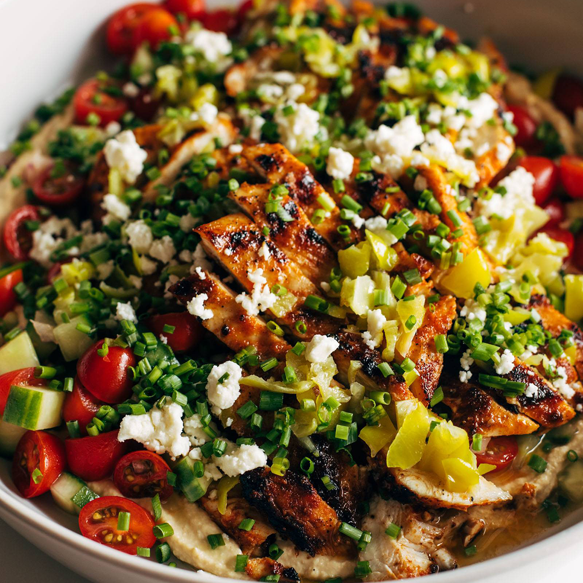 Pepperoncini chicken in a bowl with herbs and cheese on top.