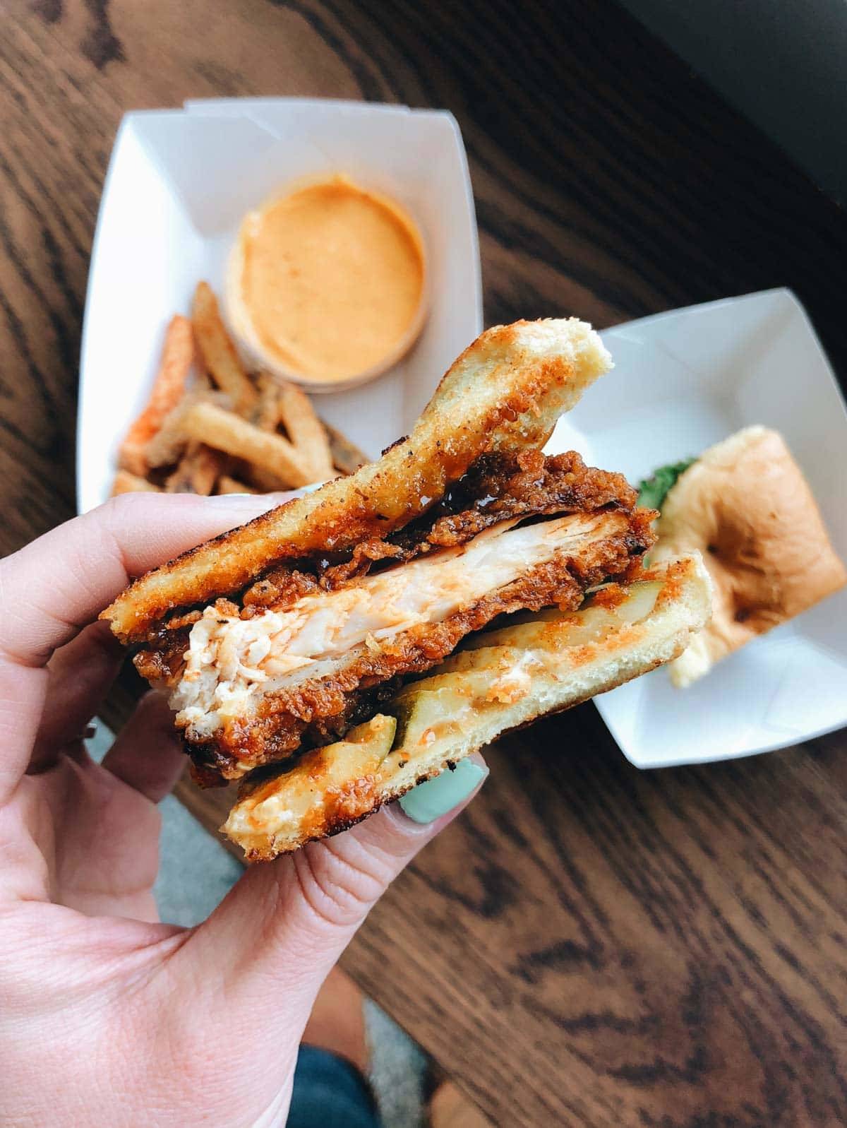 A hand holds a half-sandwich up over a table.
