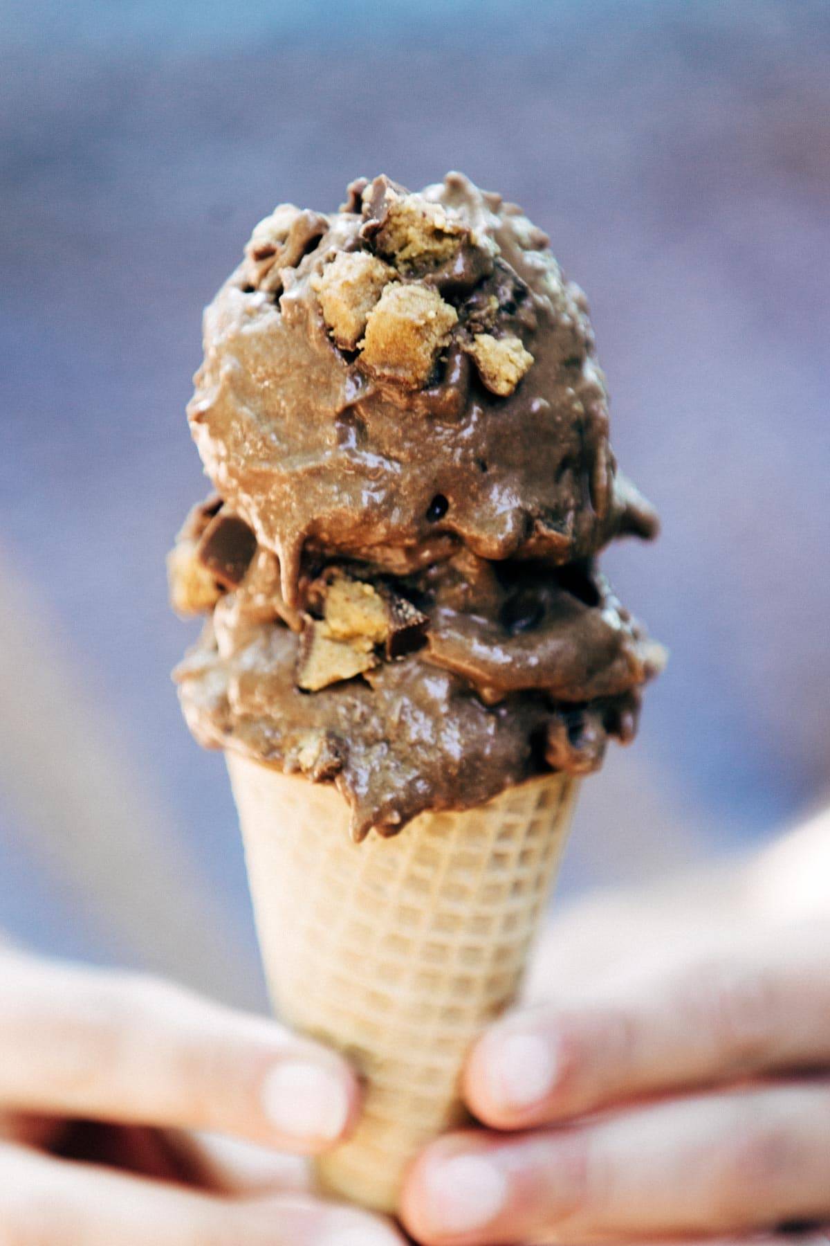 Hands holding a cone of nice cream.