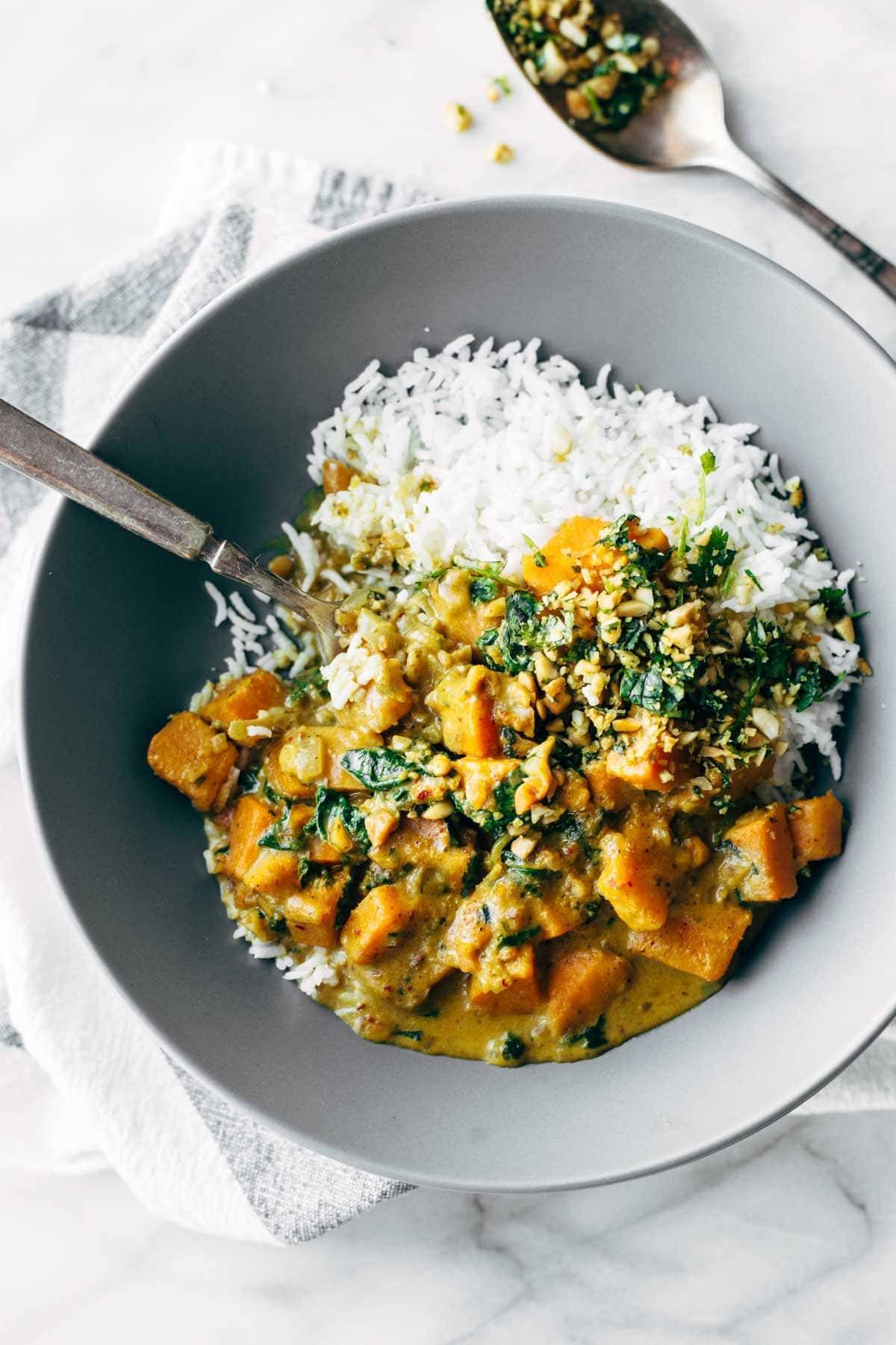 Bowl of root vegetables in sauce with rice.