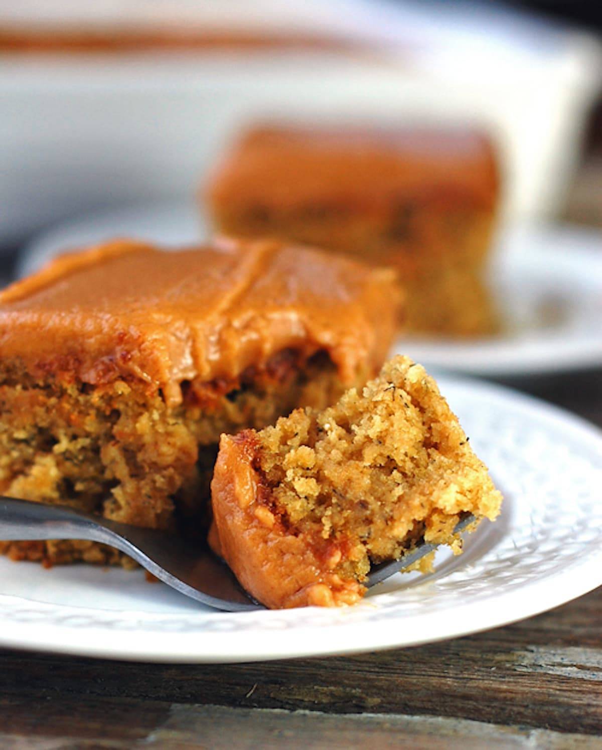 One piece of banana cake with peanut butter frosting on a fork.