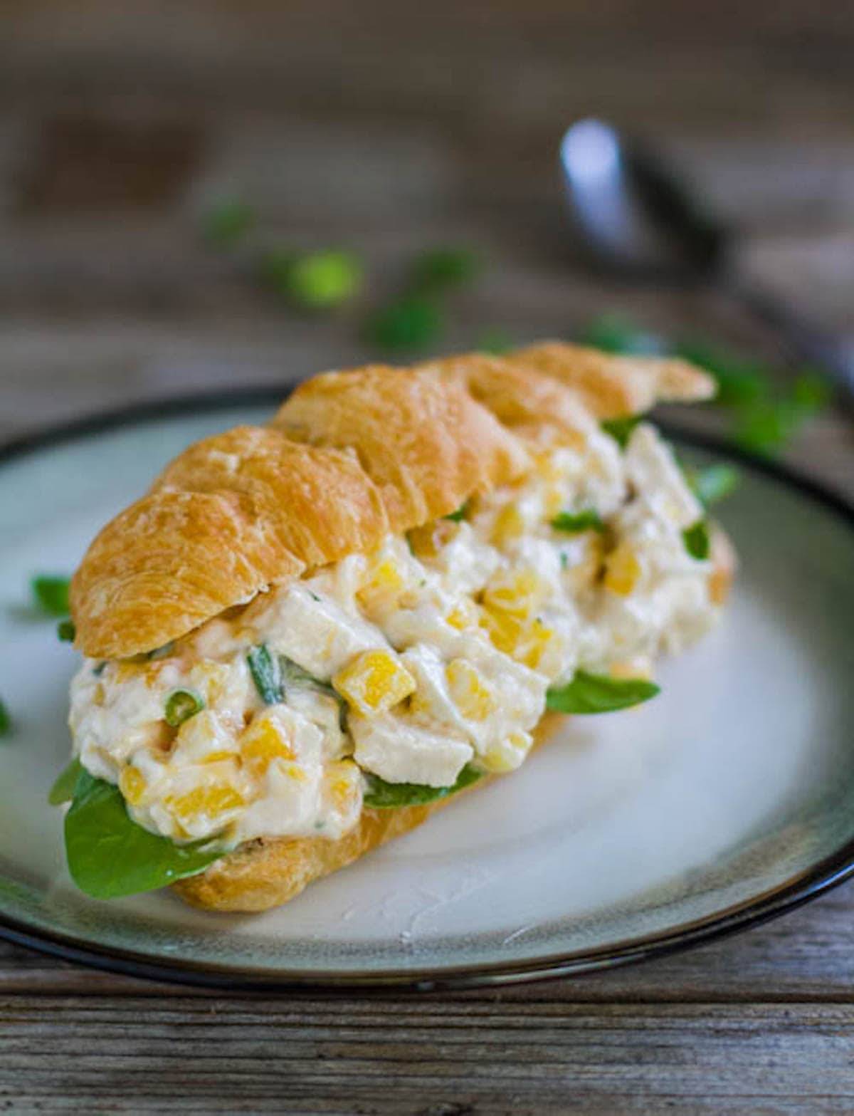 Mango chicken salad sandwich on a plate.