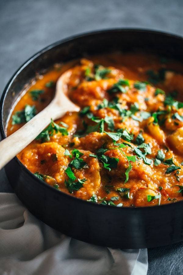 Spanish Chicken and Potatoes in a skillet with a wooden spoon.