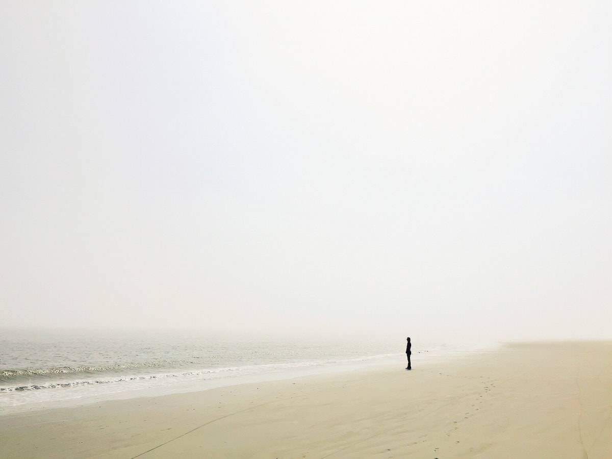Tiny person standing on the ocean shore.